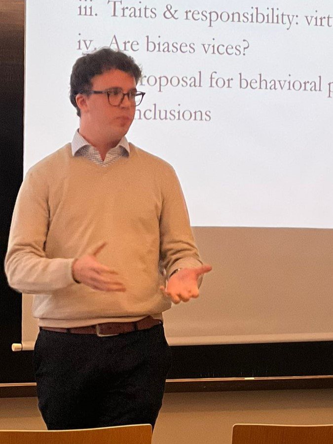 Daniel Zarama Rojas presenting in front of a slide that reads “Are biases vices?”